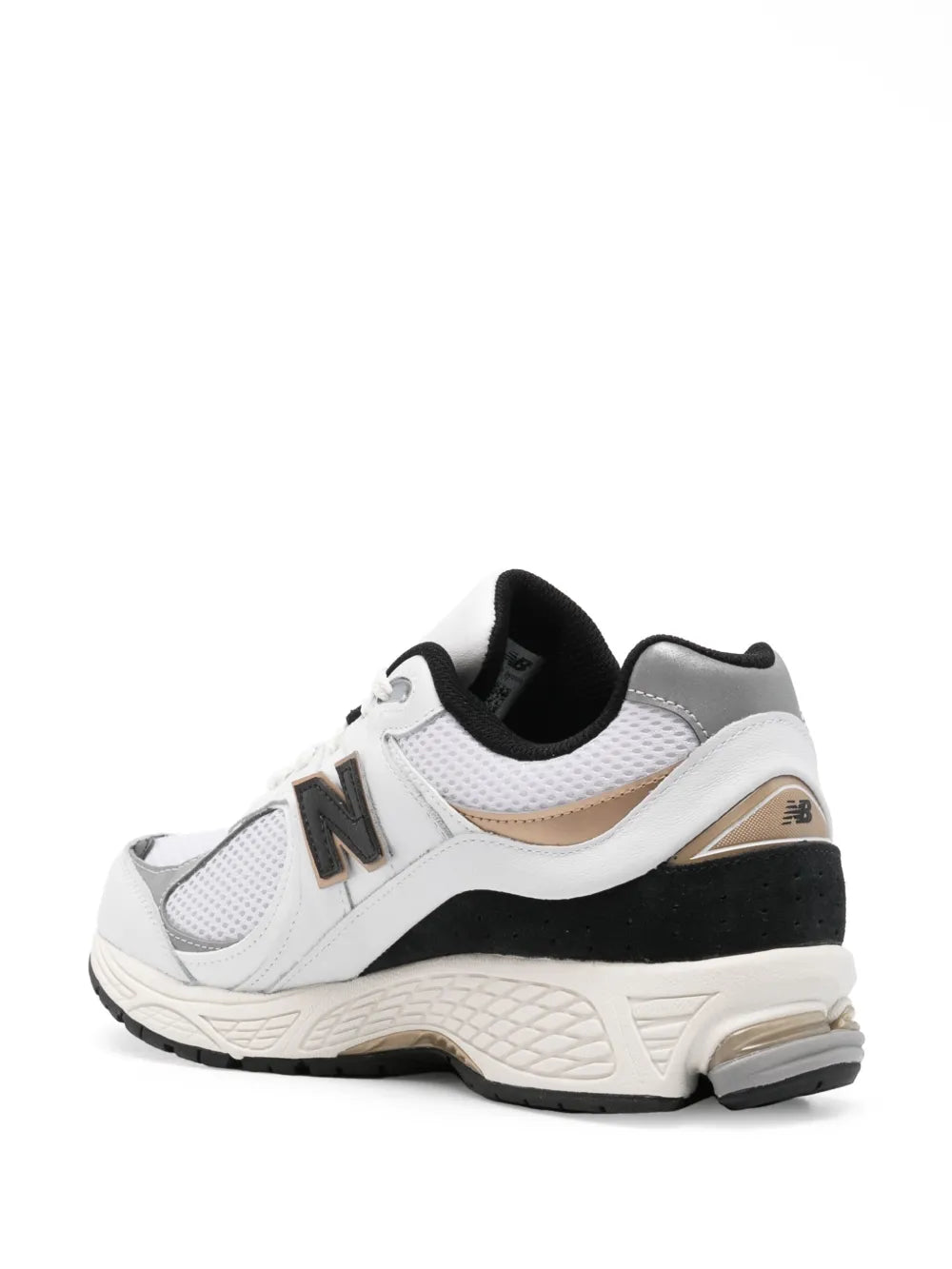 White low-top sneakers with black trim, textured outsole, and bronze accent on heel