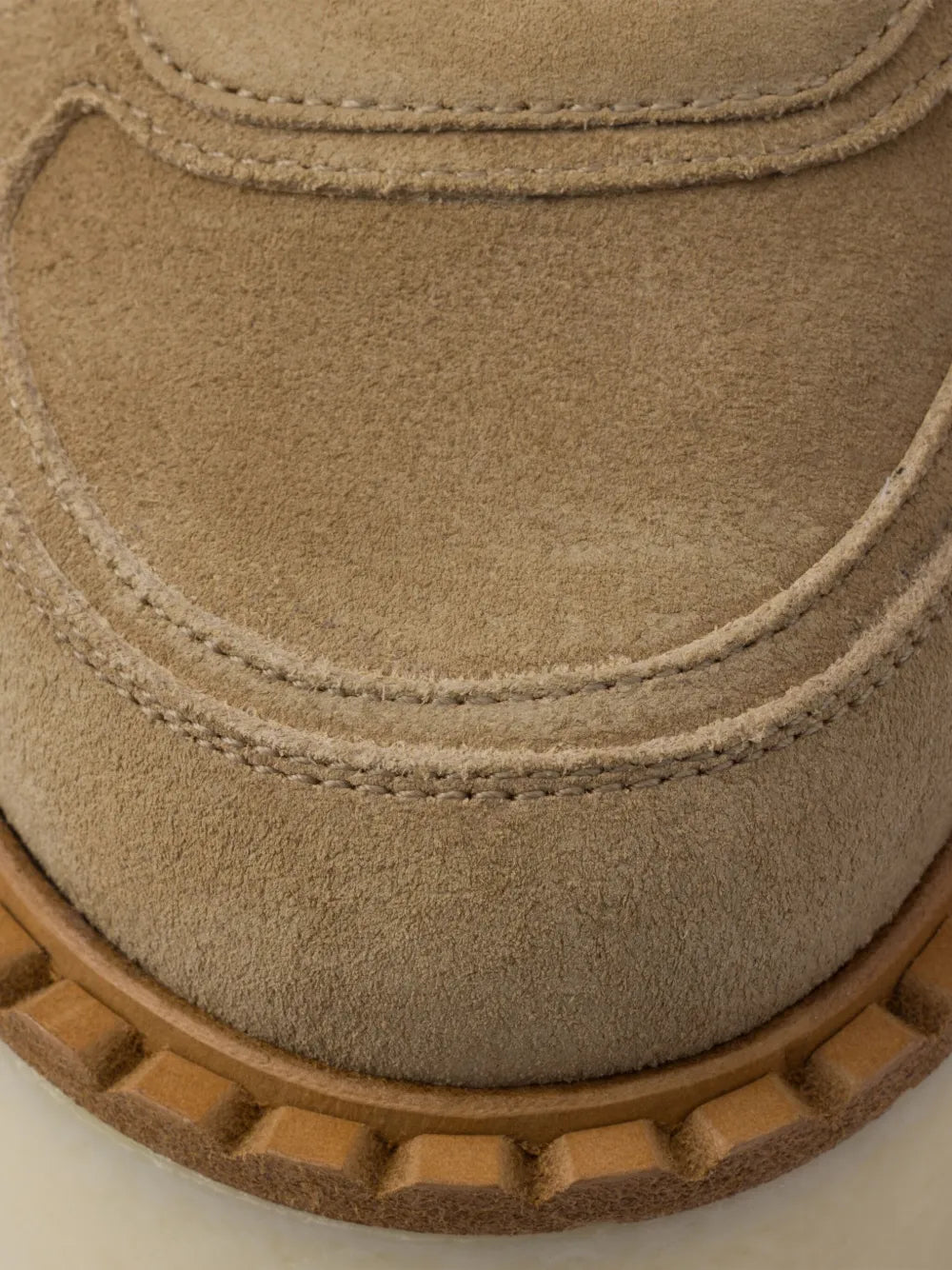 Close-up of suede sneaker upper with stitched edge detailing and rubber sole trim