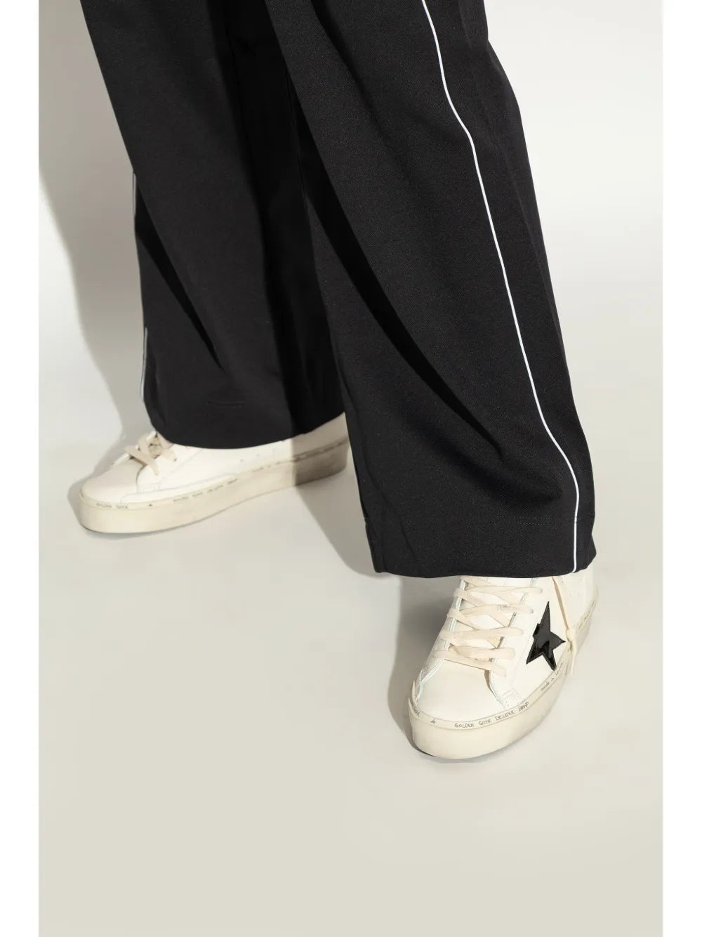 White sneakers with black star patch, worn with black track pants