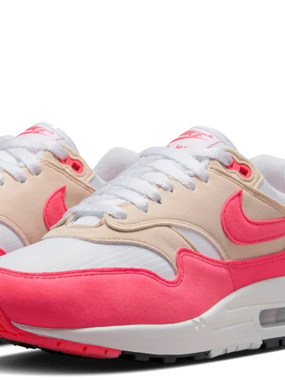 Pink-and-beige Air Max 1 sneaker close-up with white laces, swoosh and toe