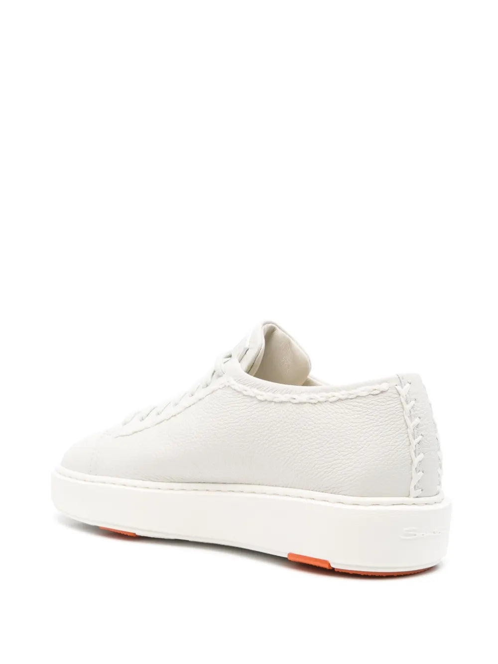 White leather low-top sneaker, rear three-quarter view with orange-trim sole