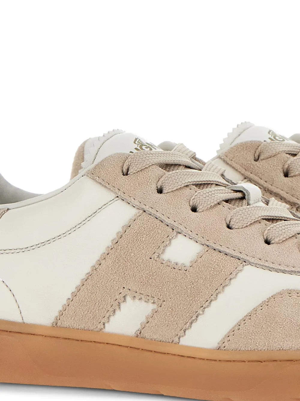 Close-up of beige suede and off-white leather sneakers with lace and stitching details