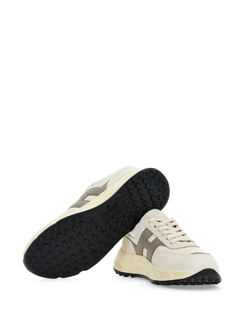 Beige sneakers shown from the bottom with black rubber tread outsole.