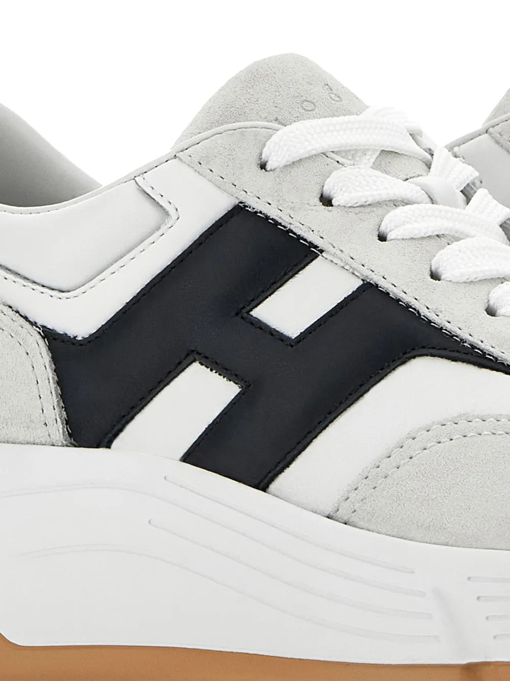Close-up of white and gray sneakers with black side logo and white lace eyelets