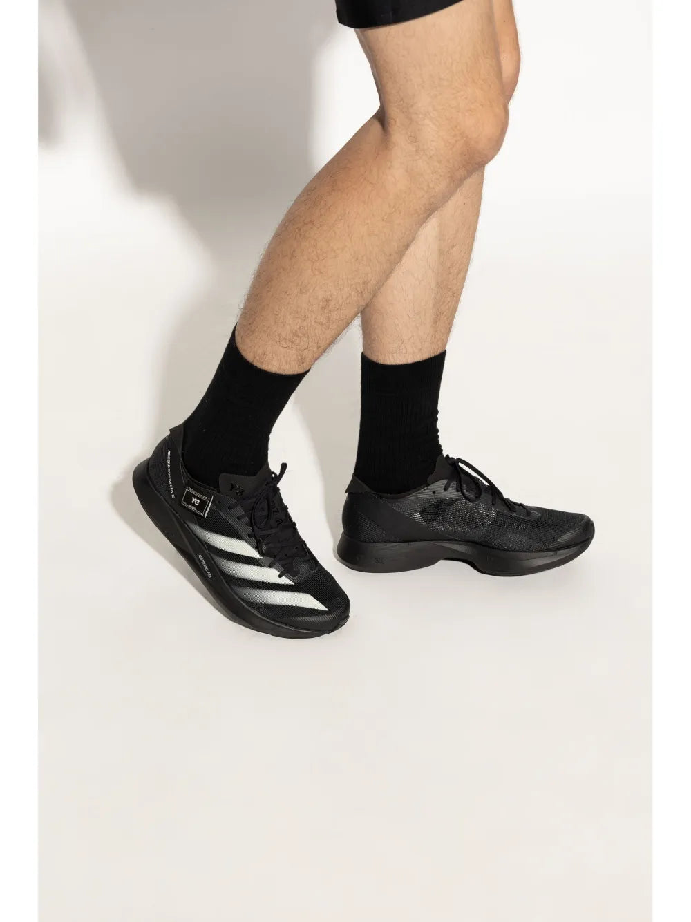Black knit sneakers with thick sole, lace-up front, and white striped accents