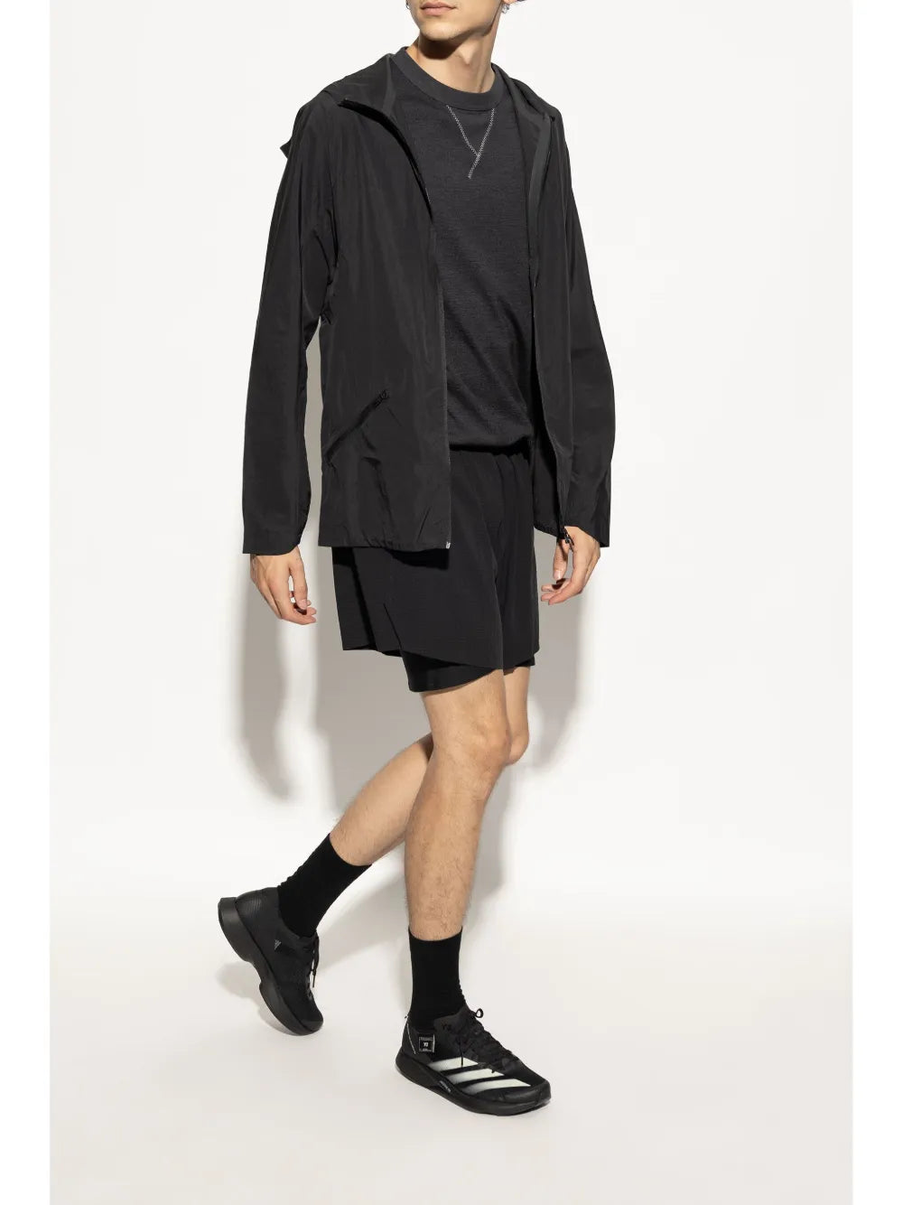 Black lace-up sneaker worn with black socks and shorts; low-profile sporty design
