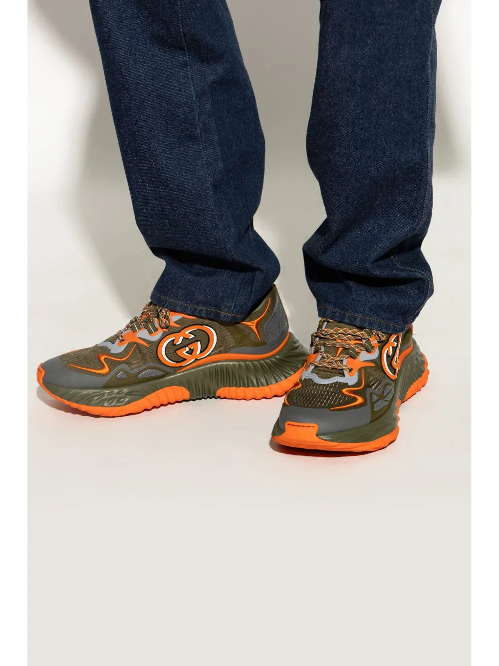 Gucci ripple sneakers on feet, olive green upper with orange trim and bold logo