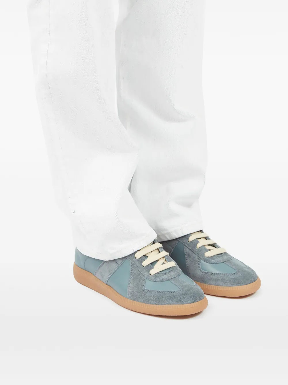 Blue suede sneakers on white pants with cream laces and gum rubber sole