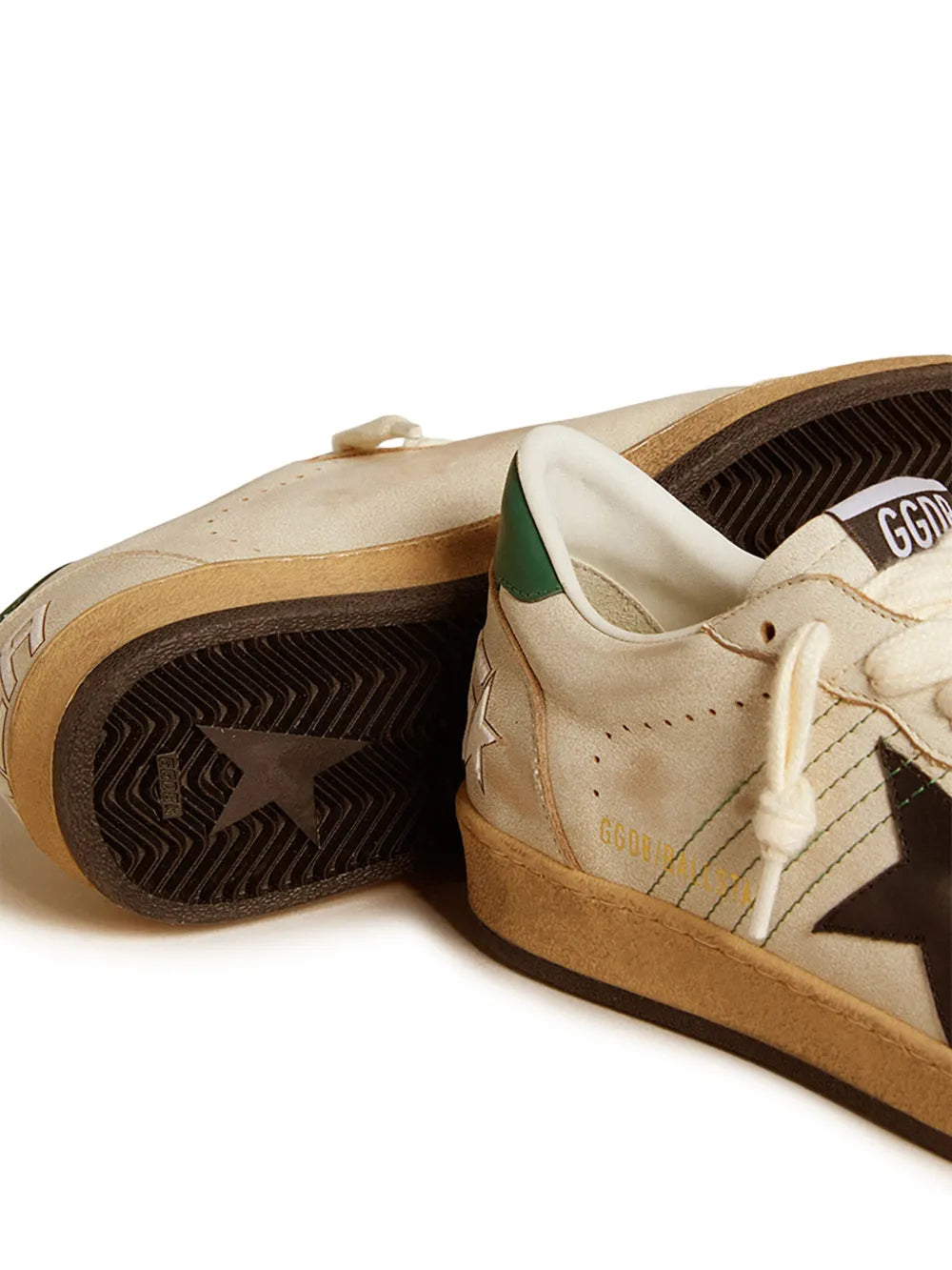 Low-top sneakers with cream uppers, black star detailing, green collar and tan sole