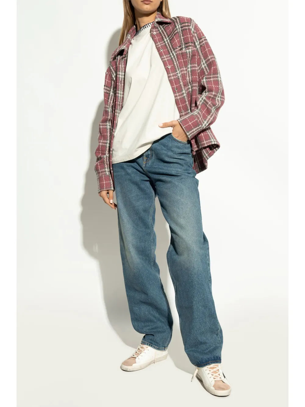 Beige and white sneakers with black star detail on feet with blue jeans