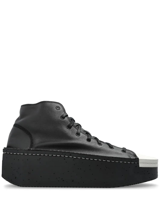 Black high-top platform sneaker with white sole, lace-up front and stitched toe cap