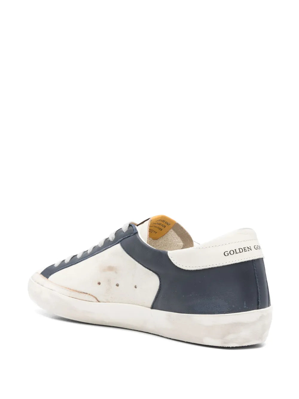 White and navy low-top sneakers with rear pull tab and gold heel logo detail