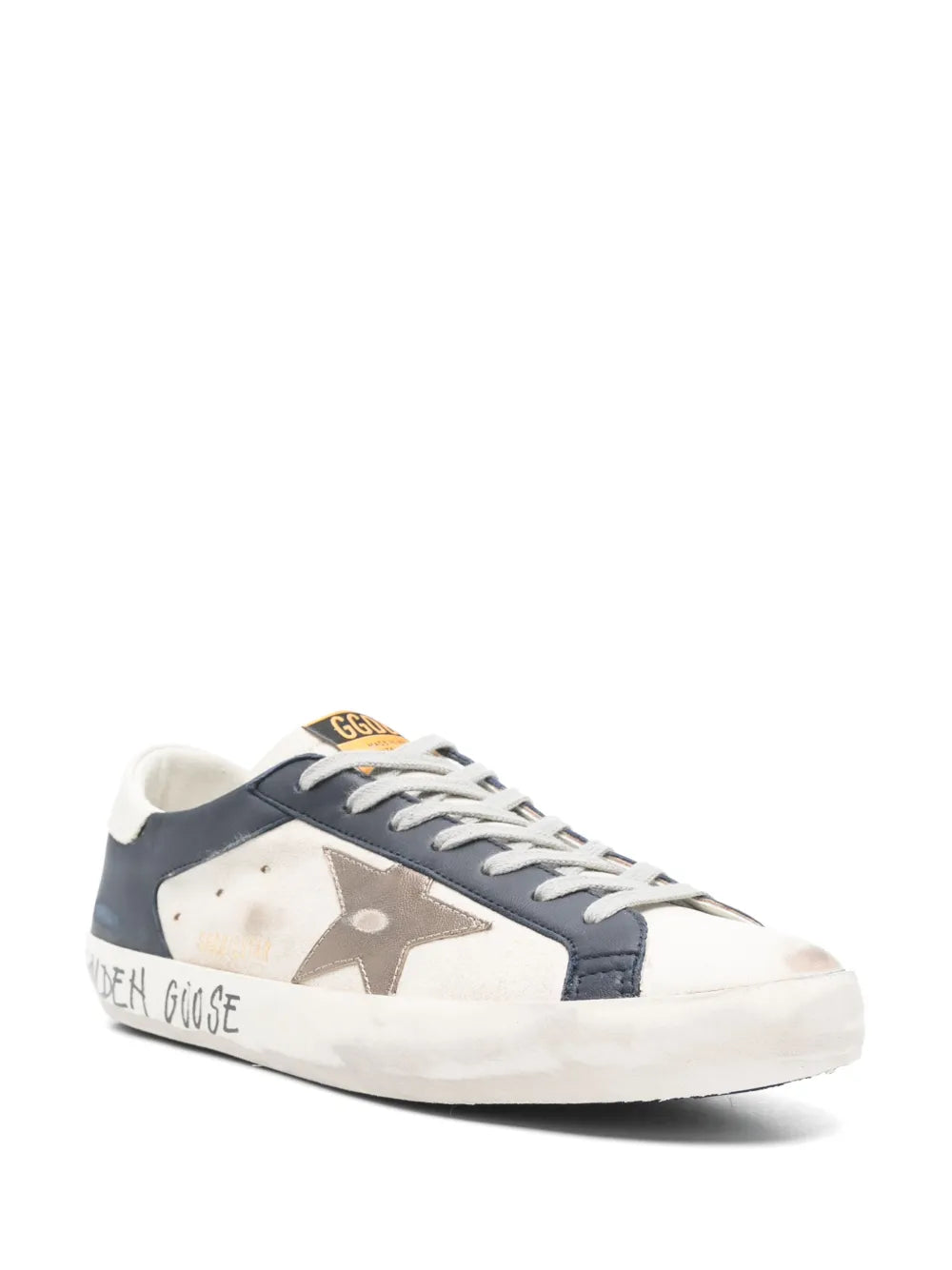 White low-top sneakers with navy quarter panels, lace-up front, and metallic star logo