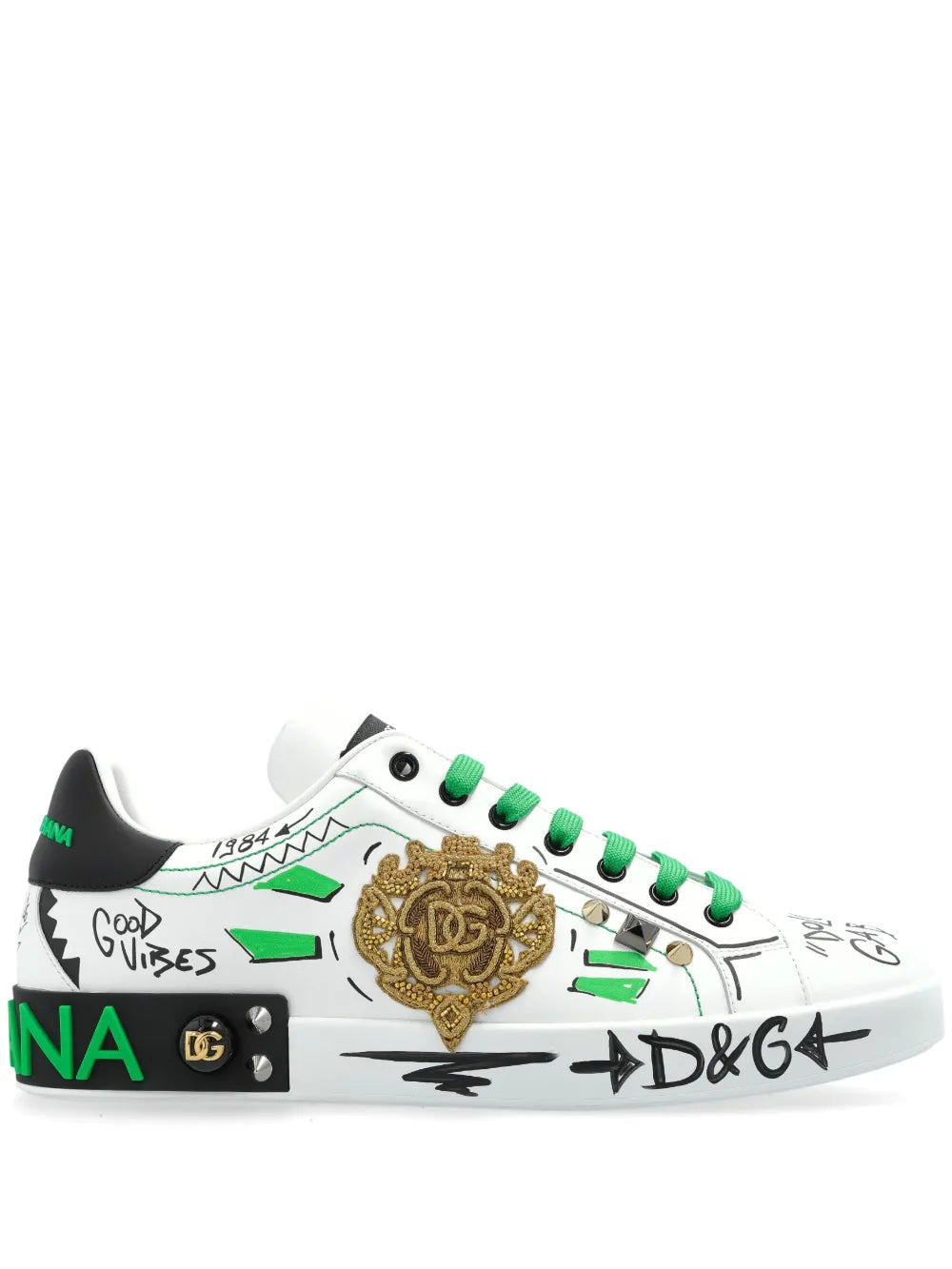White low-top sneakers with green laces and gold logo patch, graffiti-style print