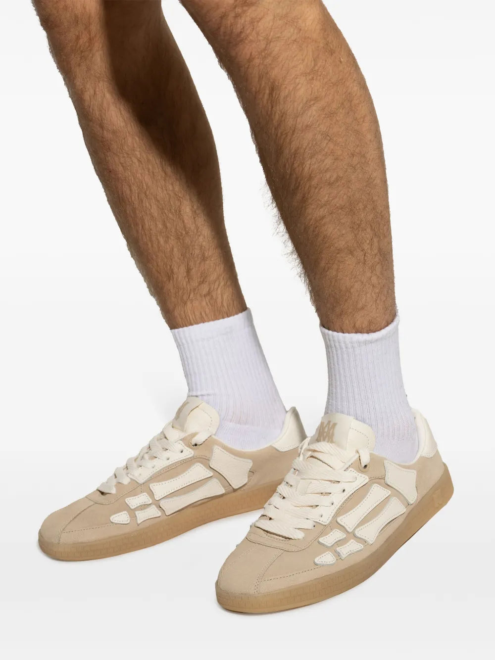 Beige lace-up sneakers on feet, white logo details and gum rubber sole