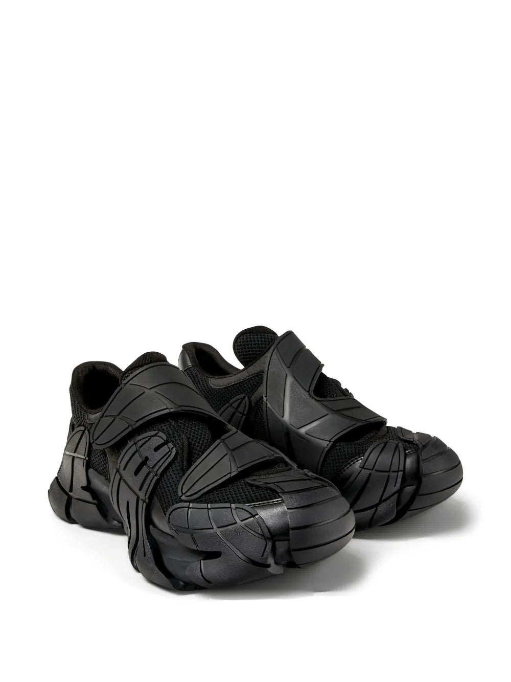 Black chunky sneakers with sculpted straps and mesh panels, angled view