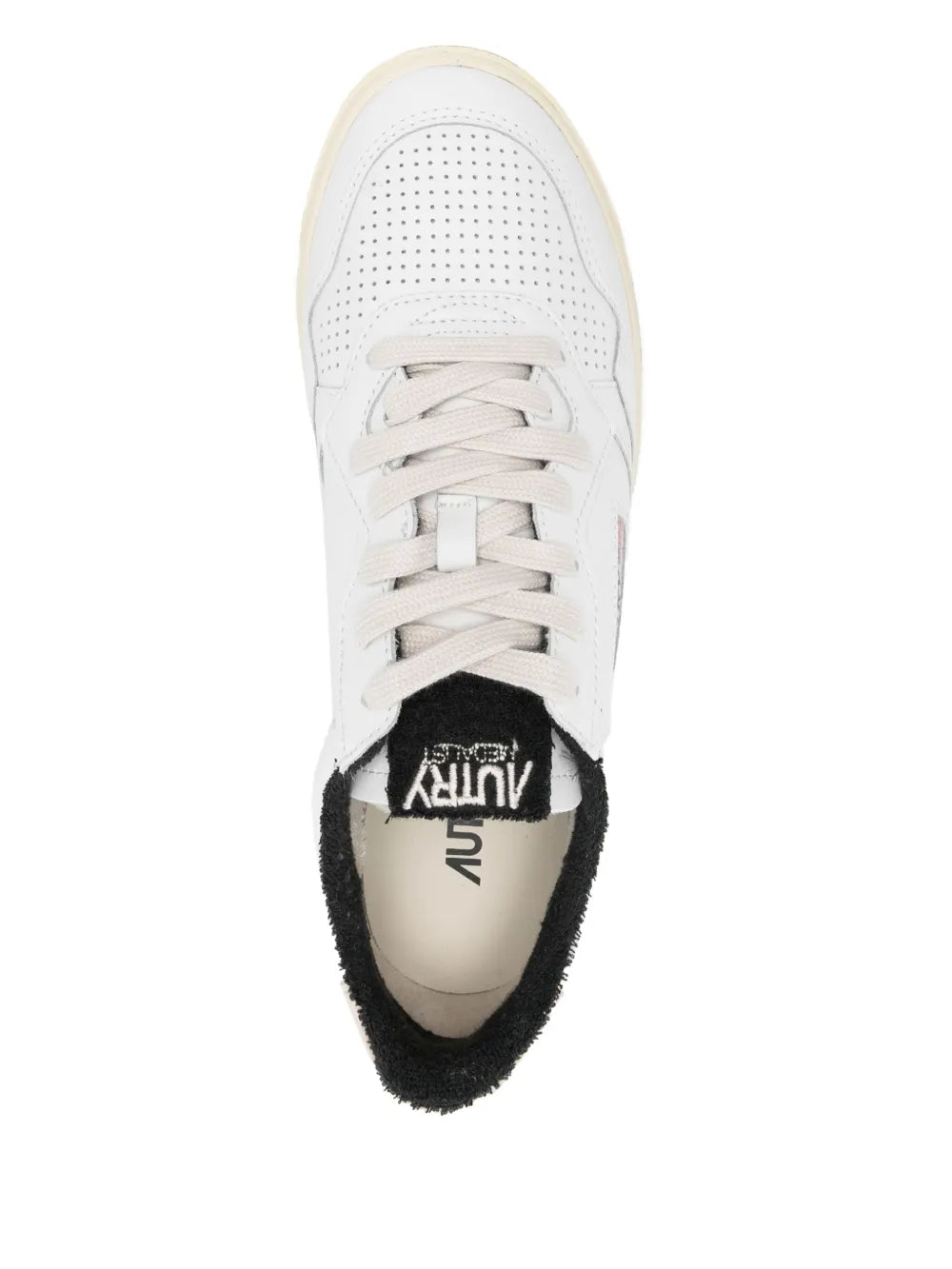 White lace-up sneaker with perforated toe and black-lined collar, textured rubber sole