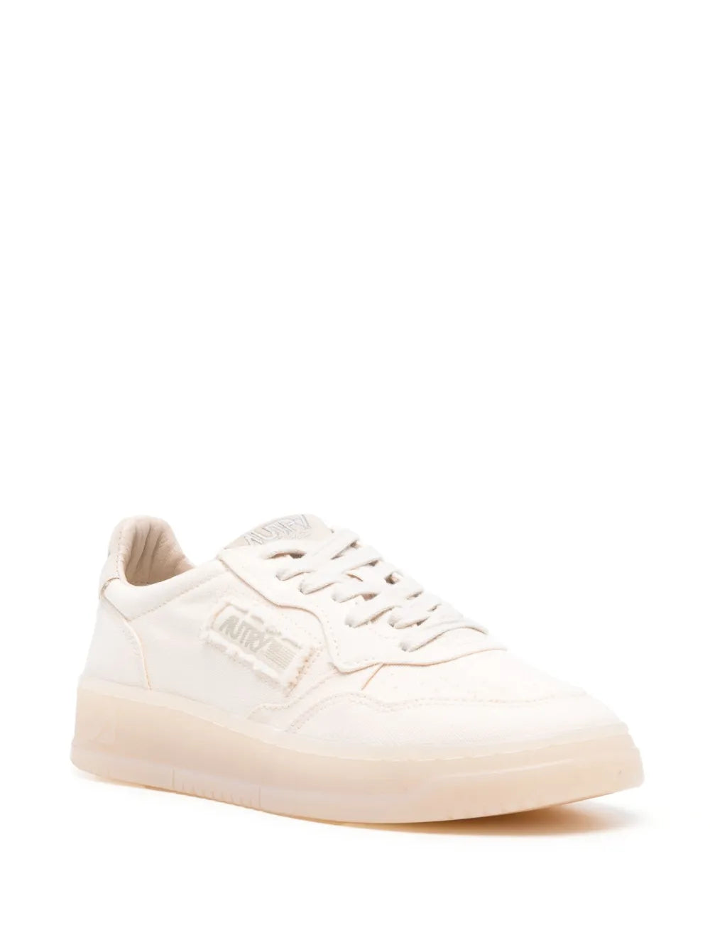 White low-top sneaker with lace-up front and side logo, angled side view