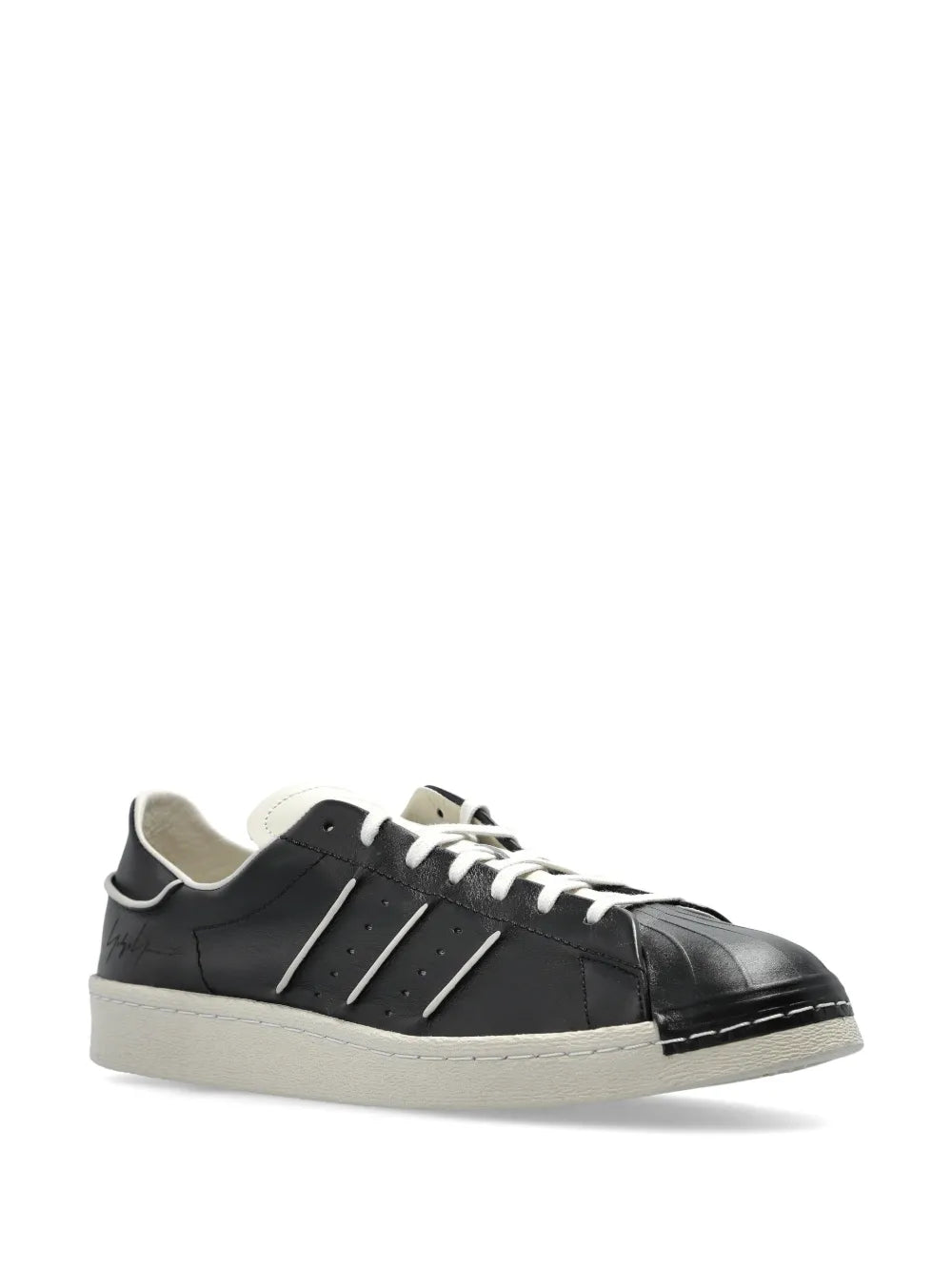 Black low-top sneakers with white laces, light suede toe cap, white edge sole
