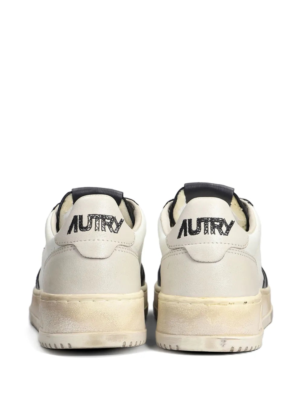 Pair of white lace-up sneakers with black heel tabs and AU.. branding on back