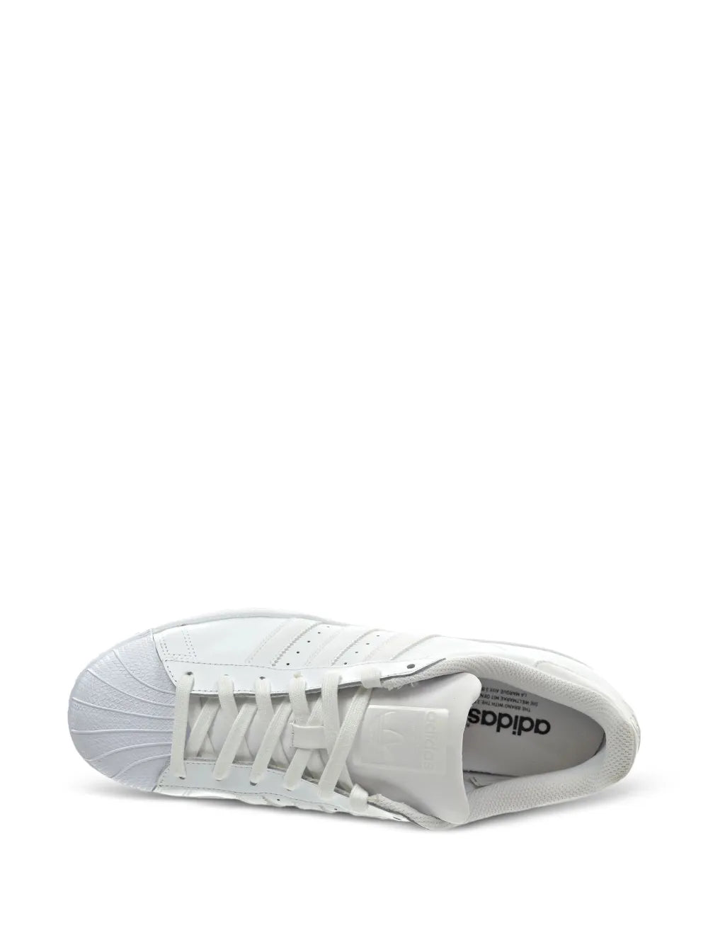 White low-top sneakers showing rubber outsole tread and adidas logo on insole