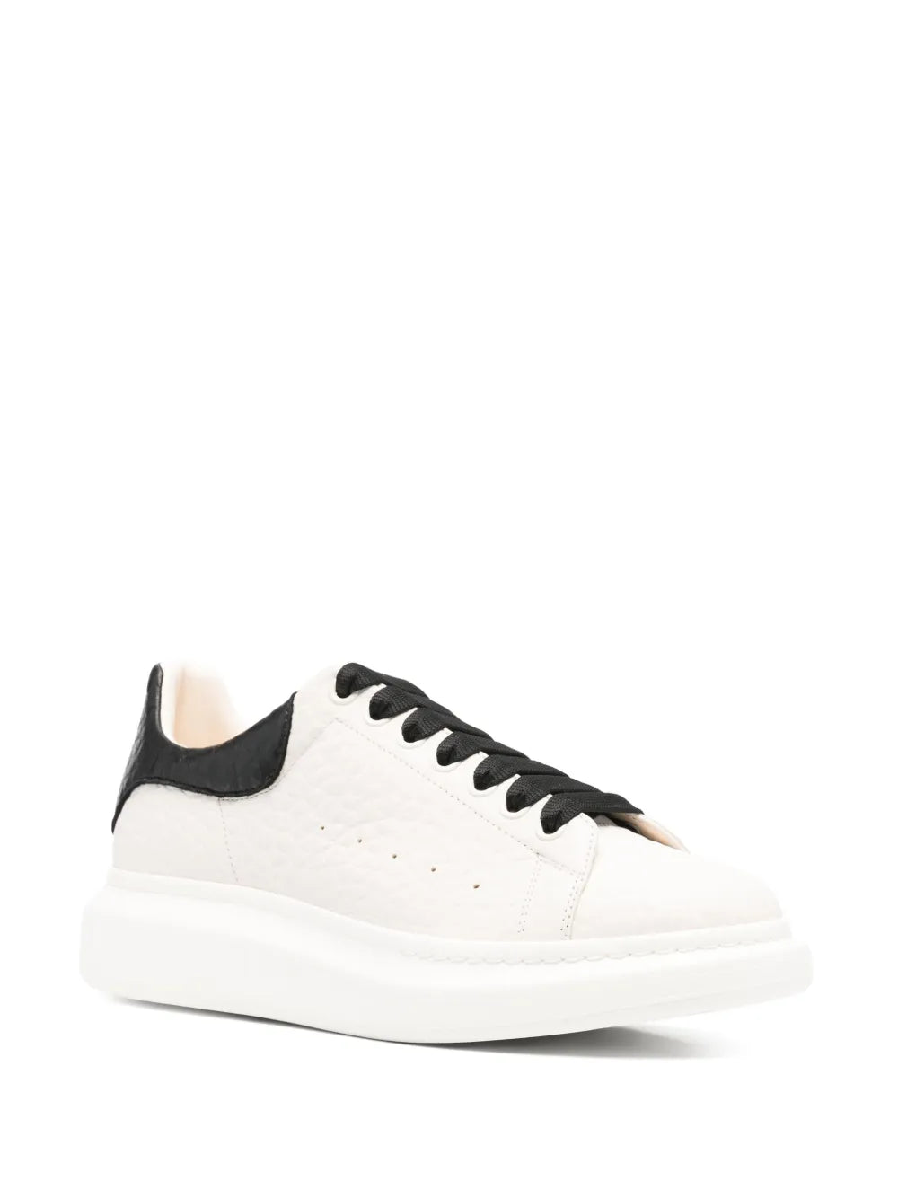 Side view oversized sneakers with cream upper, black collar, and contrast lace eyelets