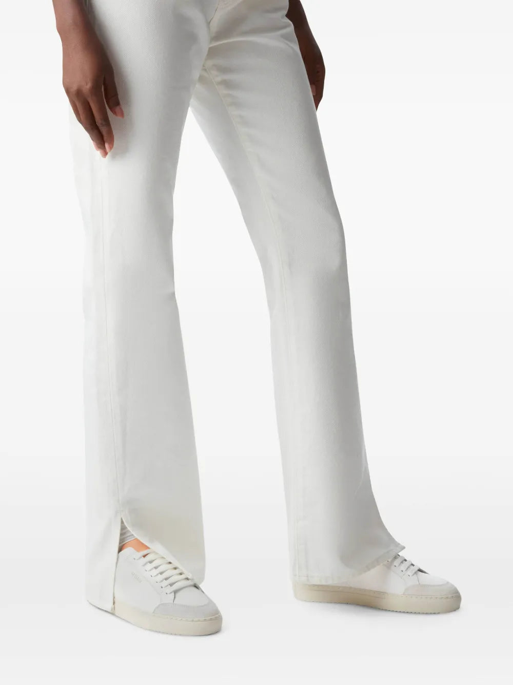 White lace-up sneakers worn with light-colored pants
