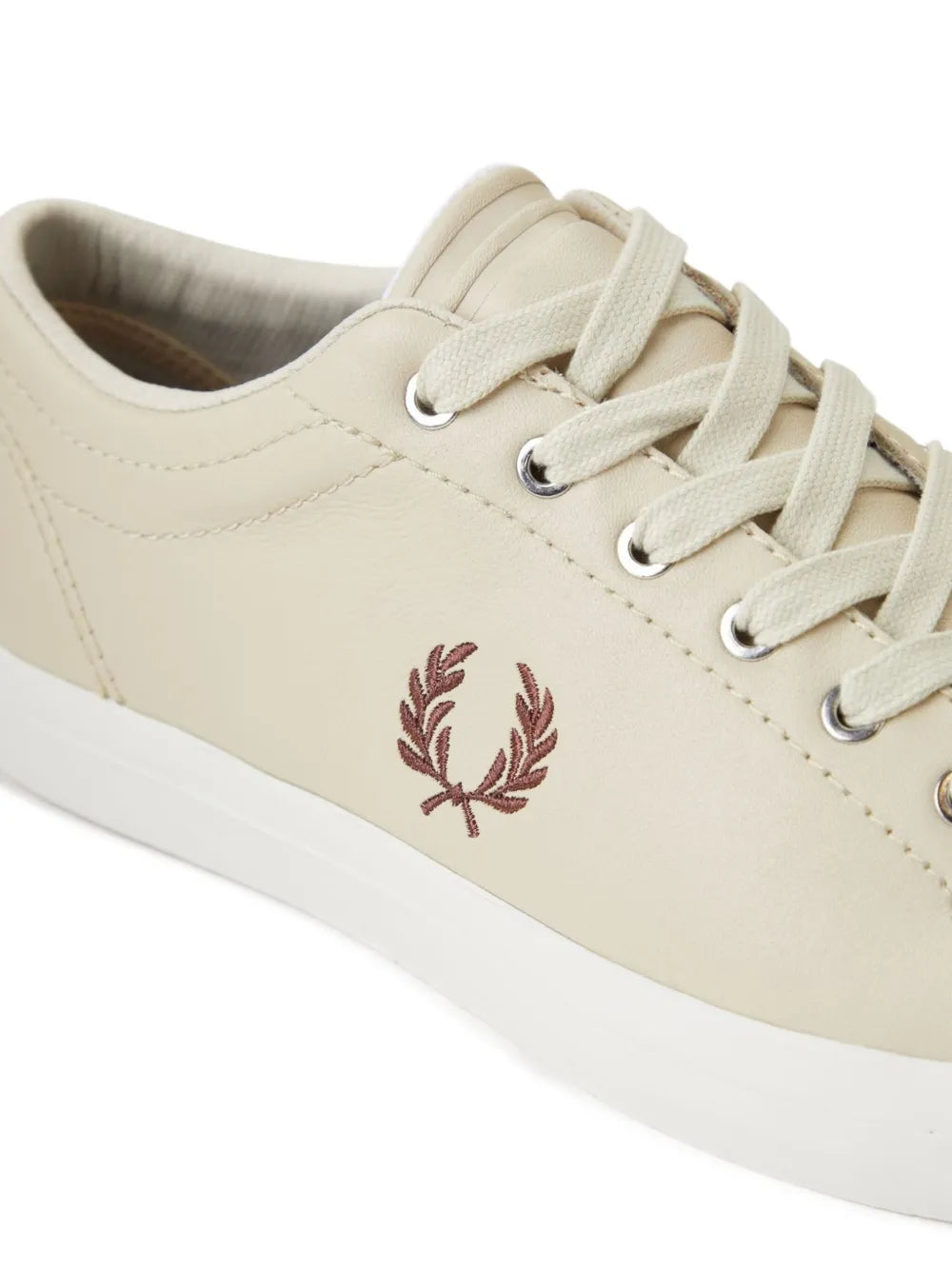 Beige leather sneaker side view with laurel emblem and white rubber sole
