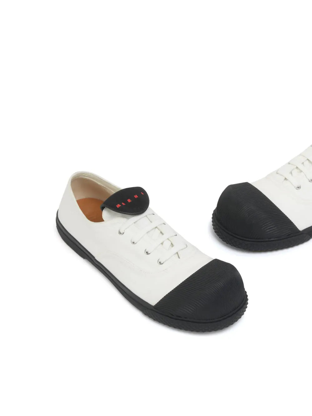 White low-top sneakers with black rubber toe caps, lace-up front, and black side panels