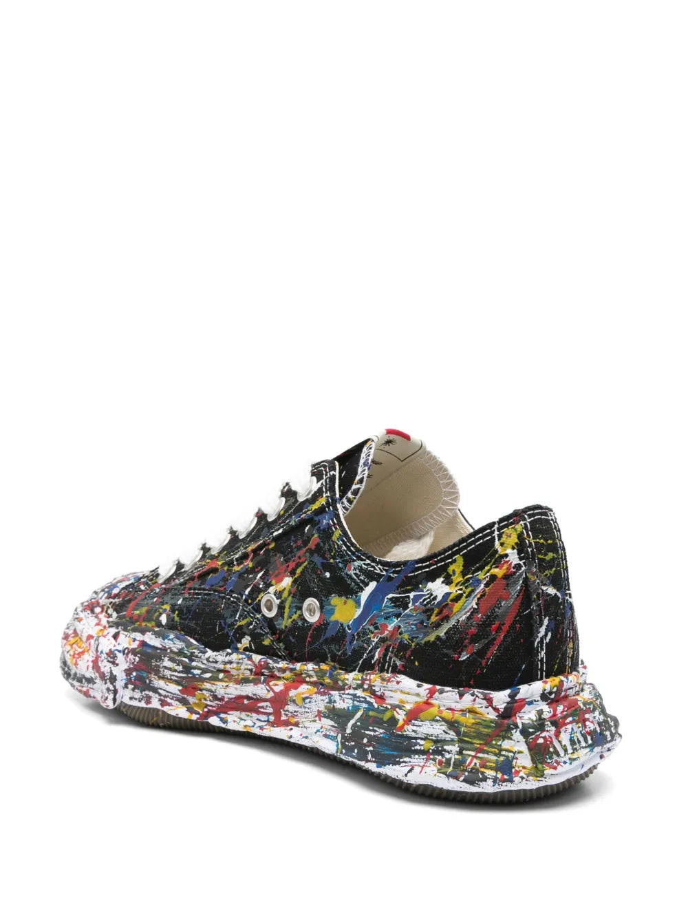Black low-top sneakers with paint-splatter print and thick speckled sole, heel side