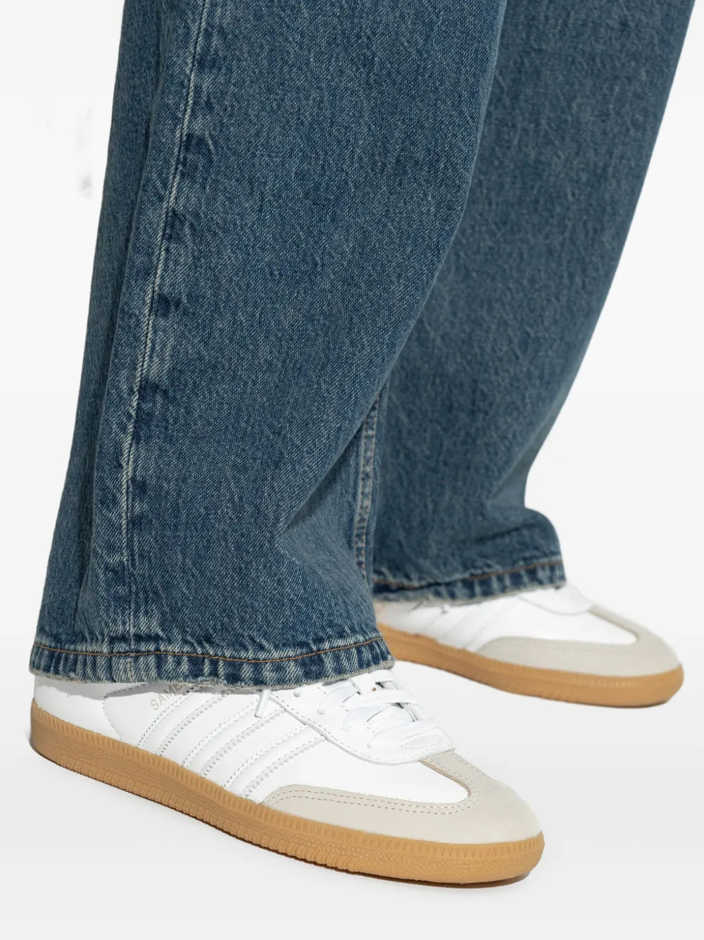 White adidas sneakers with gum sole worn with dark blue wide-leg jeans