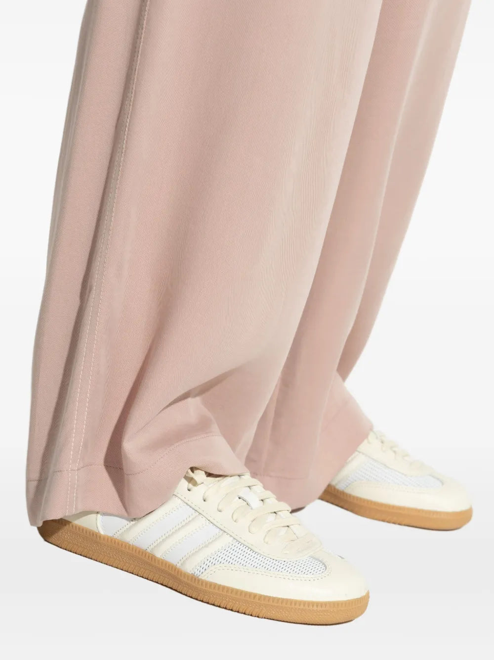 Close-up of light beige sneakers with light blue stripes, laces, and gum sole