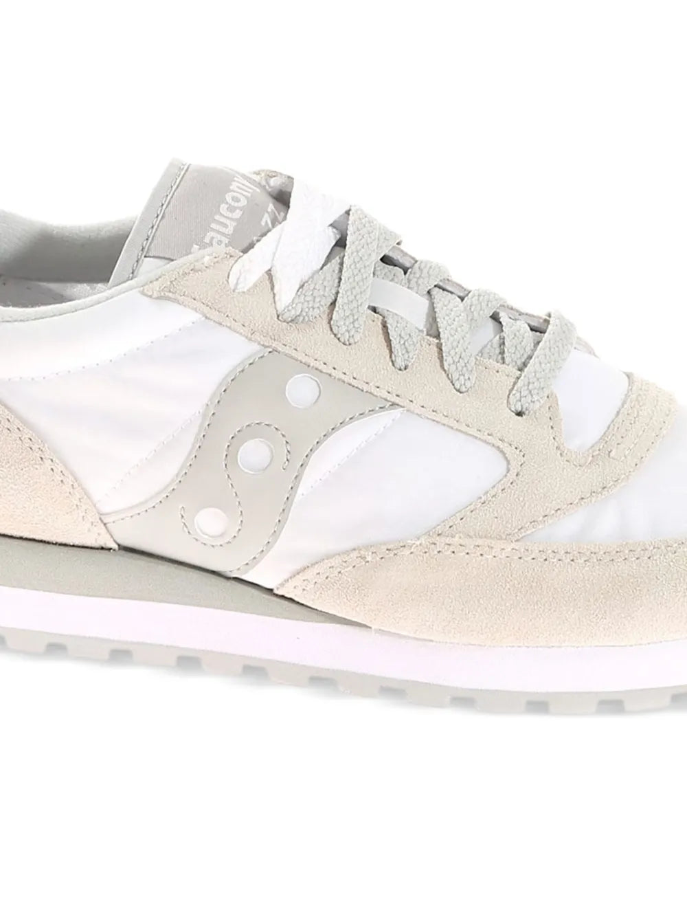 Side view of white and beige low-top sneaker with lace-up and circular logo