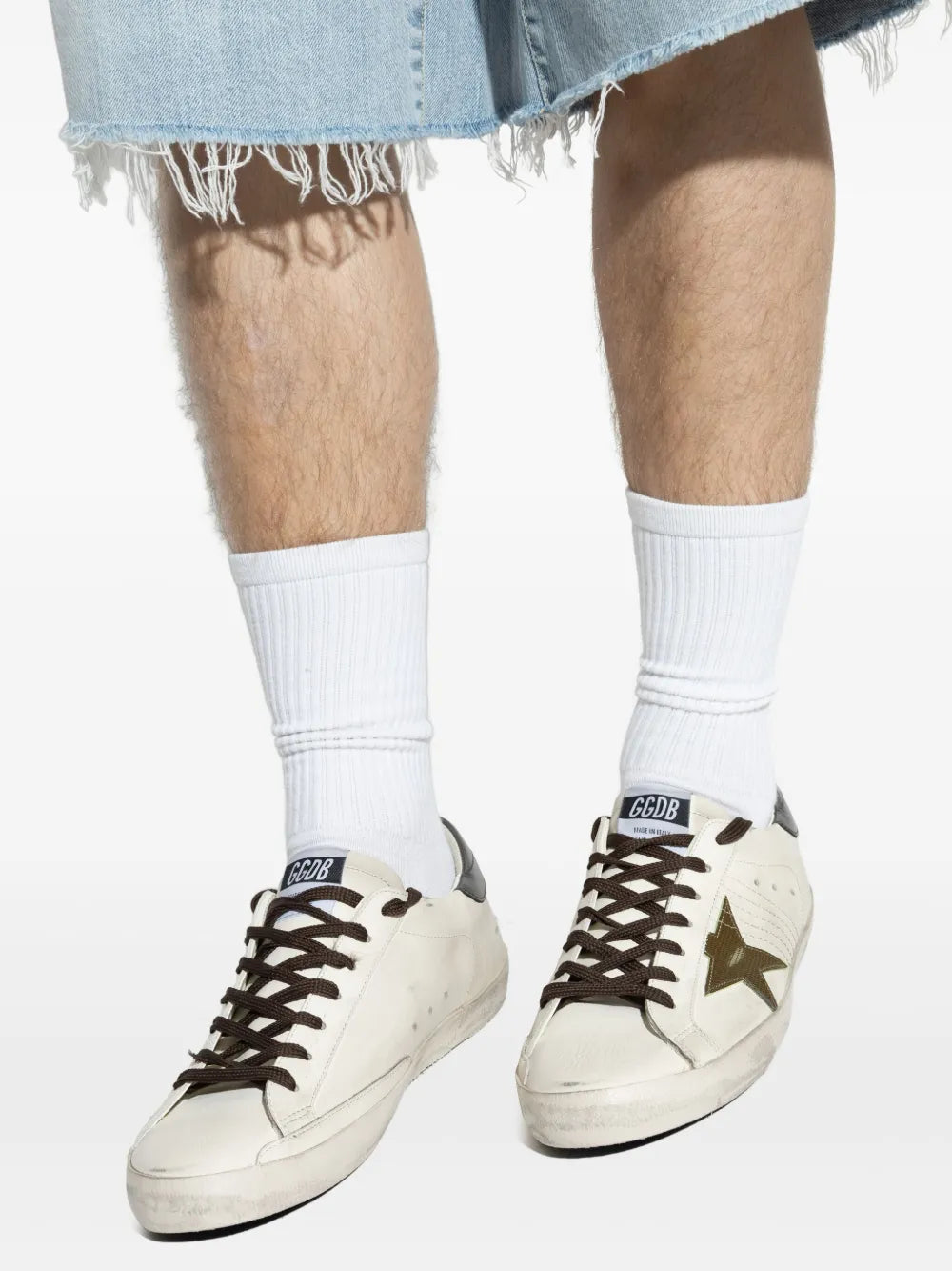 Golden Goose Super Star sneakers close-up, white uppers with gold star and brown laces