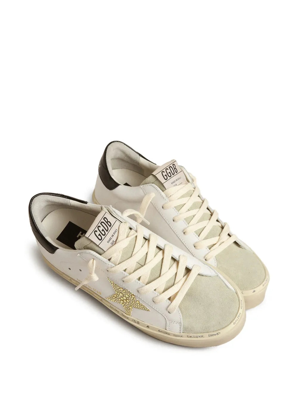 Two white leather lace-up sneakers, gold star on side, beige rubber sole