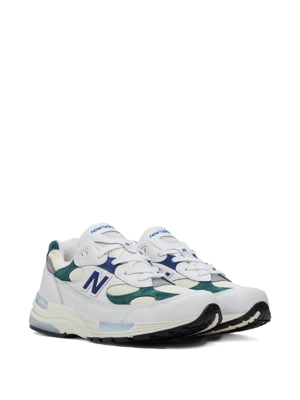 White New Balance sneakers with green and navy accents, lace-up, black rubber outsole