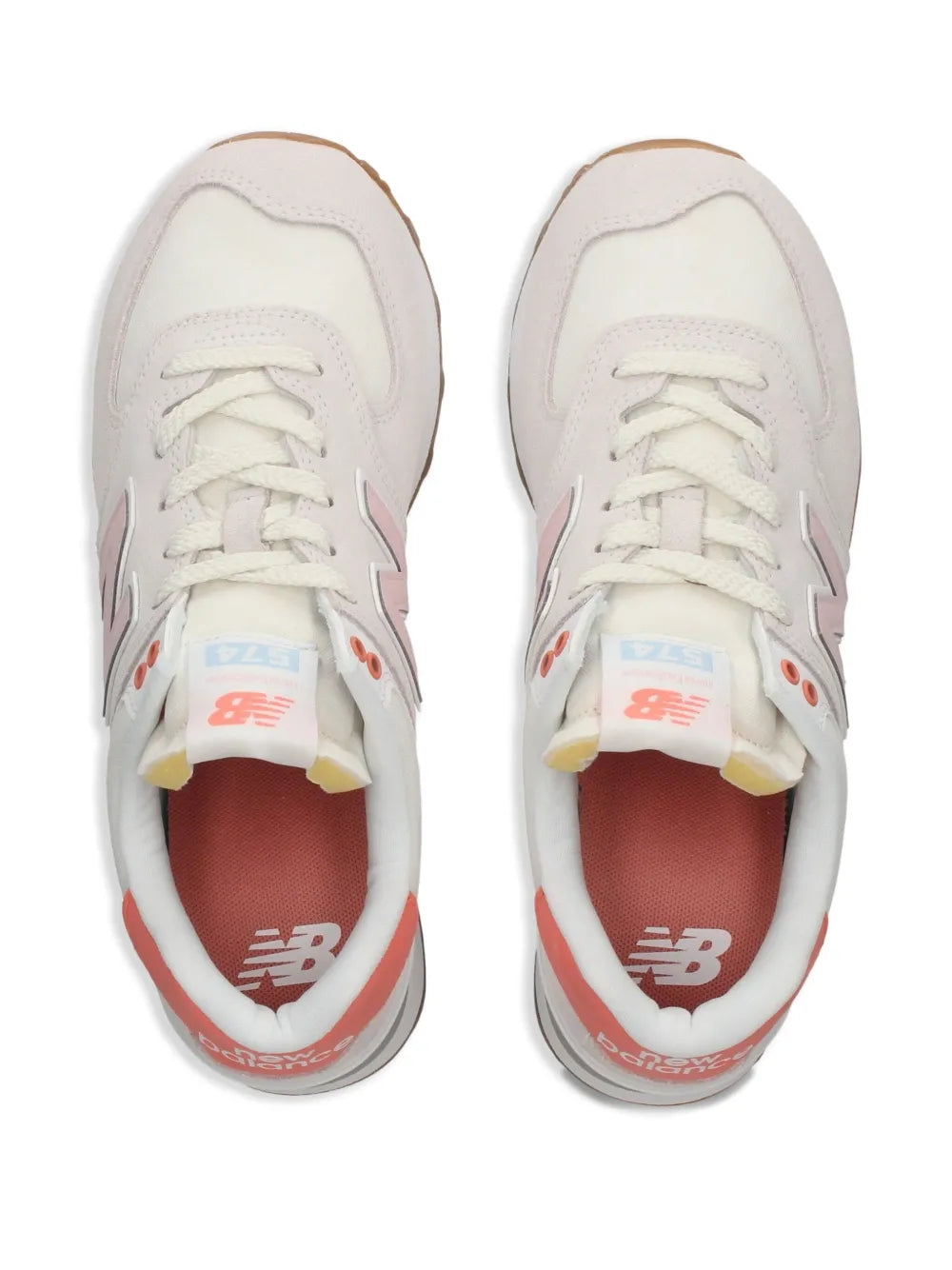 Pair of white New Balance 574 sneakers, lace-up front with coral liner accents