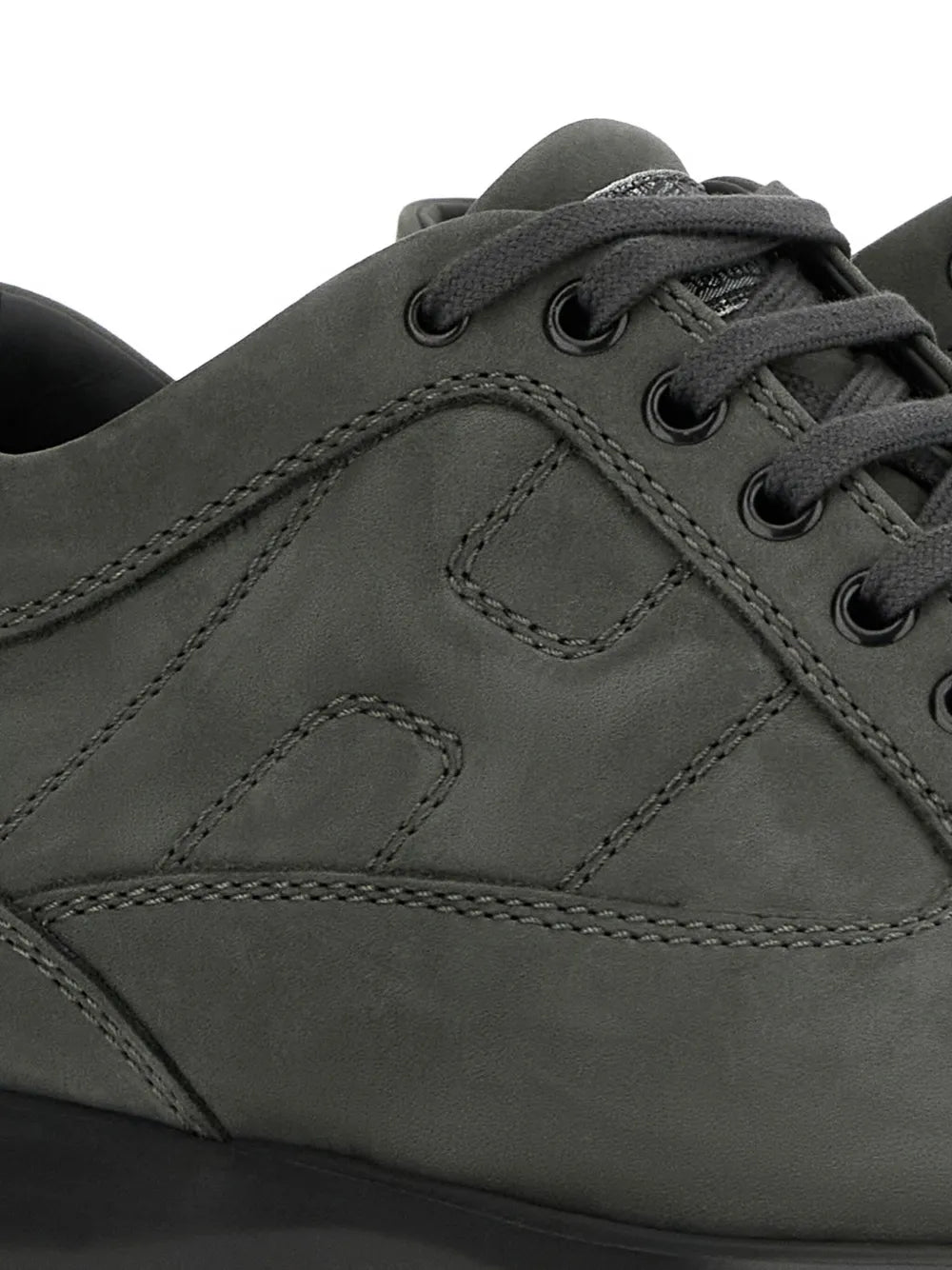 Charcoal grey sneaker upper close-up with lace eyelets and stitched overlays