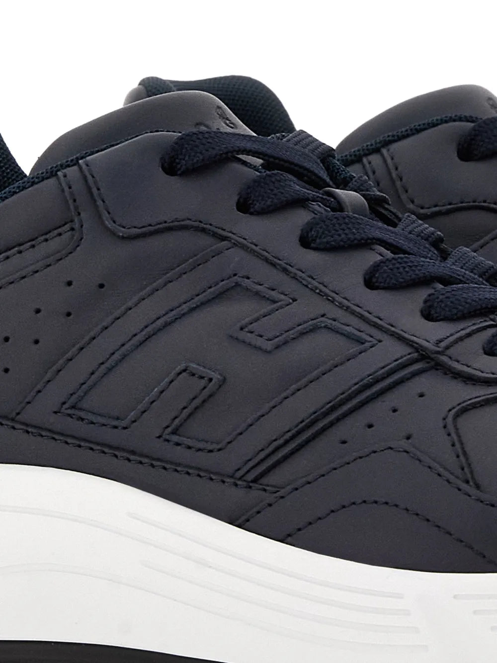 Dark blue sneaker upper close-up with lace eyelets and embossed logo details