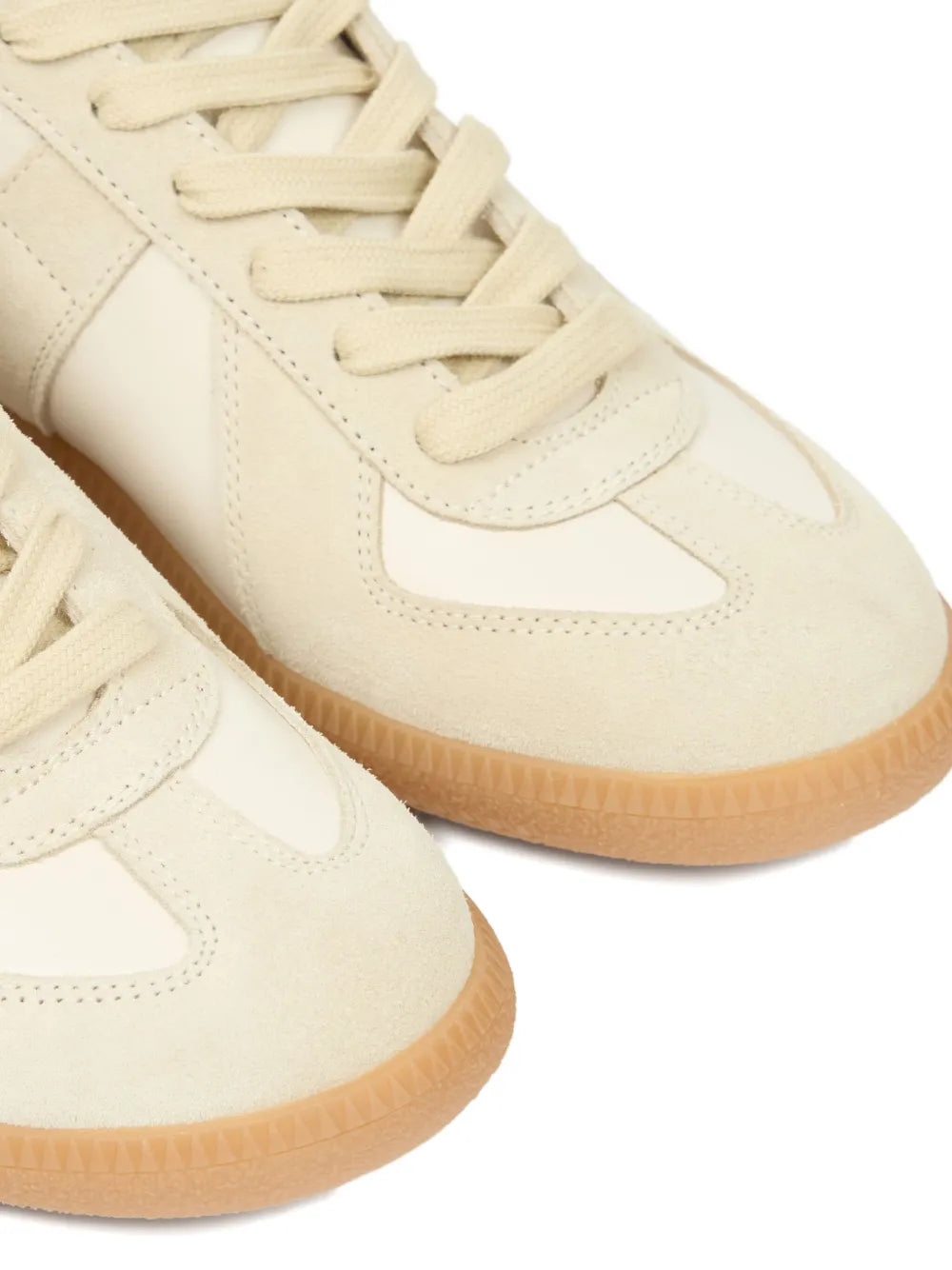Beige low-top sneakers close-up of laces, side panel, and gum sole