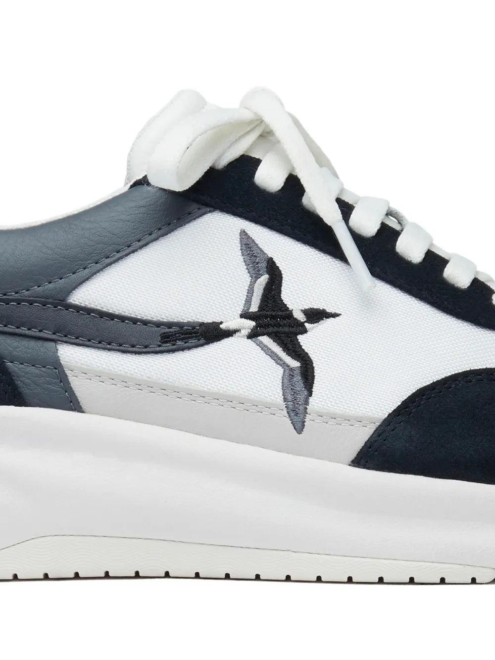 White lace-up sneakers with navy side panels and bird logo on quarter.
