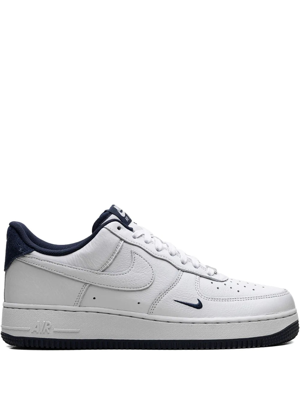 White low-top Nike lace-up sneakers with navy Swoosh, heel tab, and cushioned sole