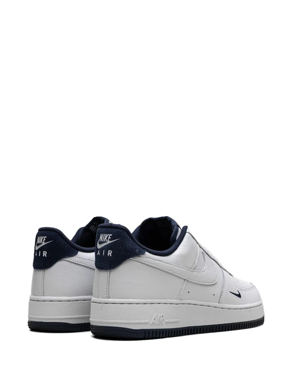 White Nike low-top sneakers with navy heel tab and 'AIR' branding on back