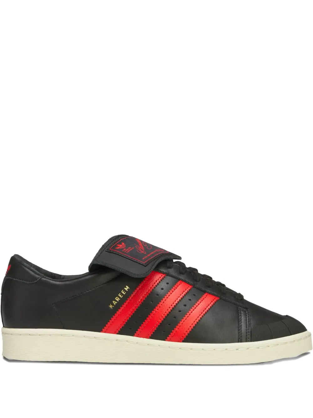 Black low-top adidas sneakers with red stripes and cream sole