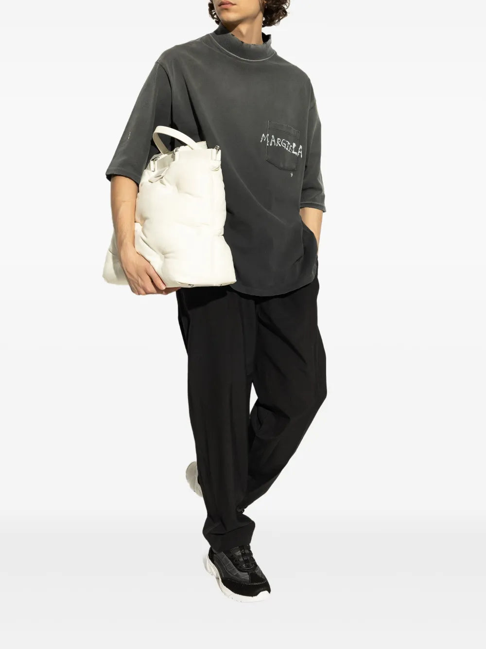 Black panelled sneakers with white midsole worn with black trousers