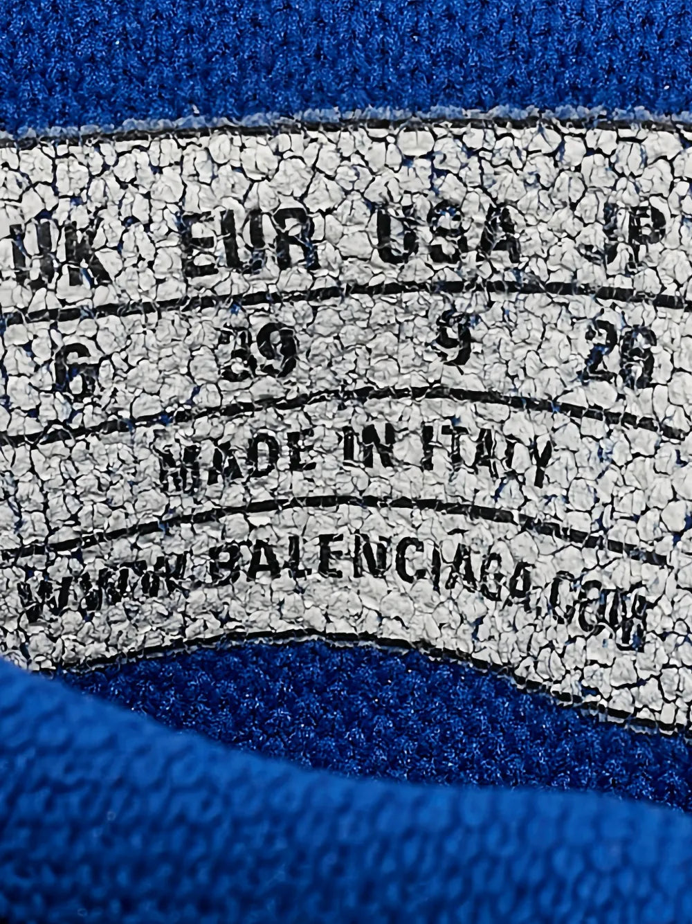 Close-up of white label text on interior sock cuff of blue knit sneaker