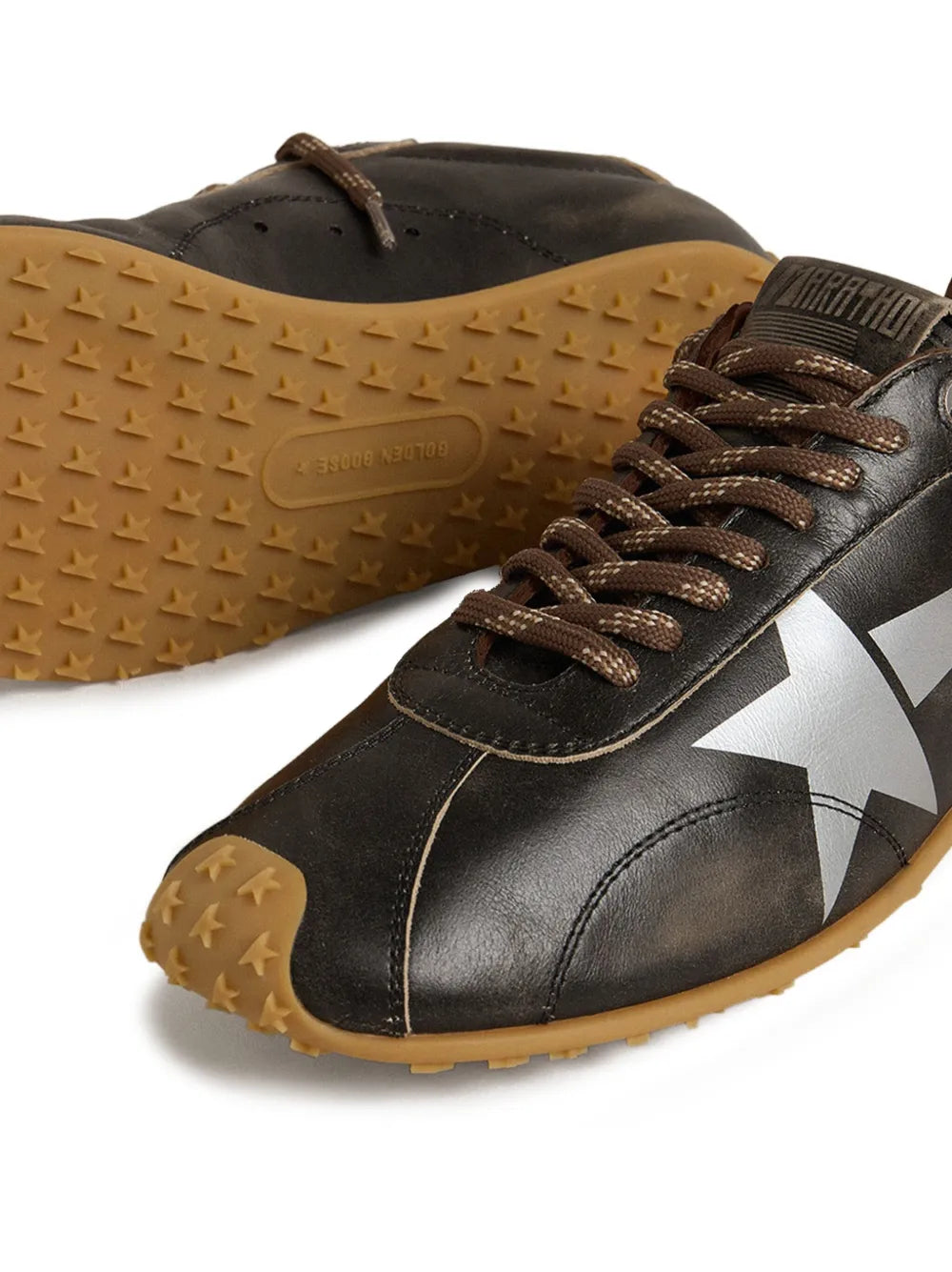 Dark brown leather sneakers close-up with star-dotted rubber sole and laces