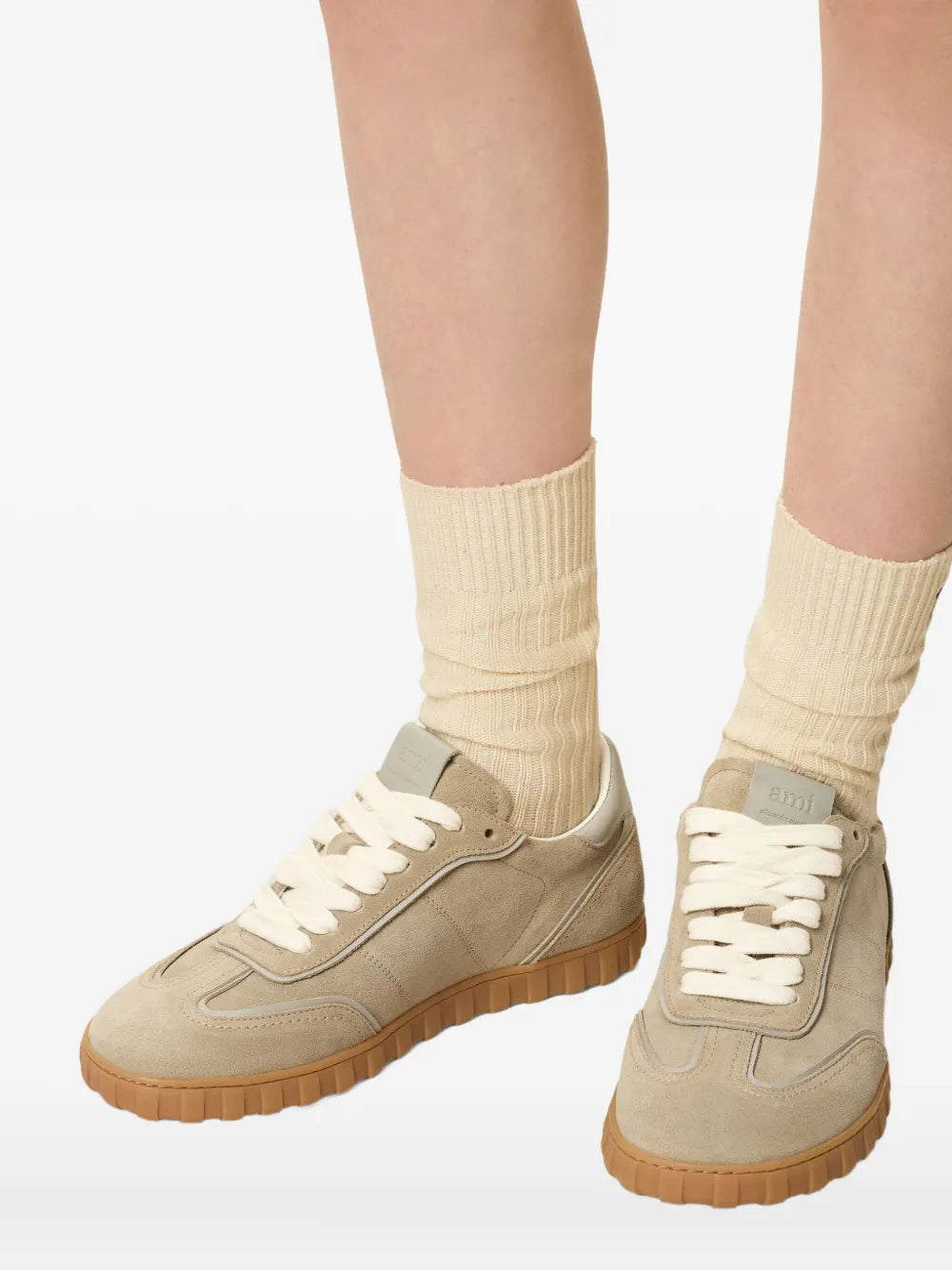Beige leather low-top sneakers with white laces, styled with light cream socks