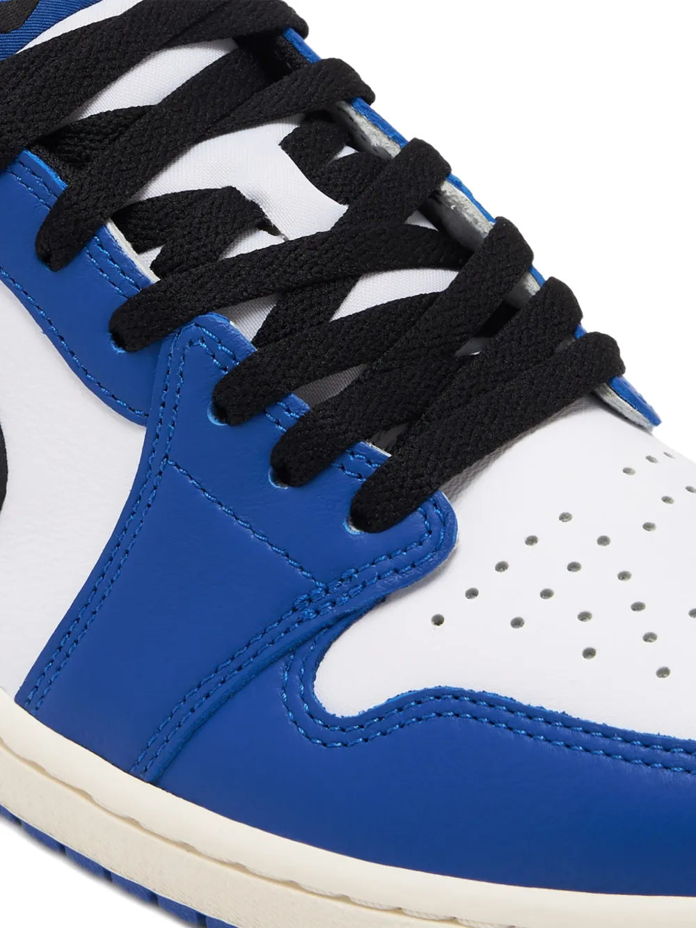 Close-up of blue and white low-top sneaker with black laces and perforated toe