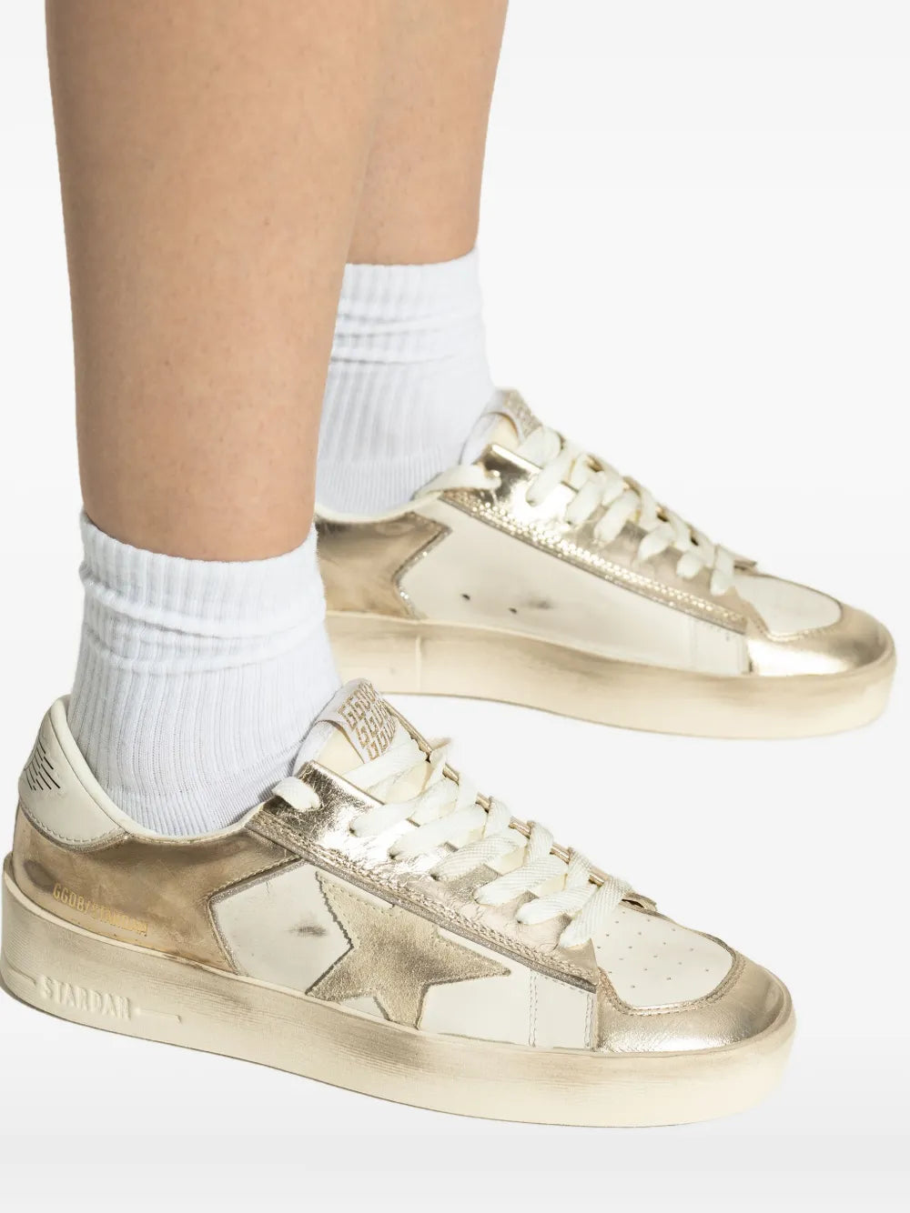 Golden Goose leather sneakers close-up, metallic gold and white leather laces
